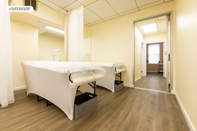 interior space with visible vents, a paneled ceiling, baseboards, and wood finished floors