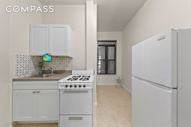 kitchen with white appliances, light tile patterned floors, baseboards, a sink, and tasteful backsplash