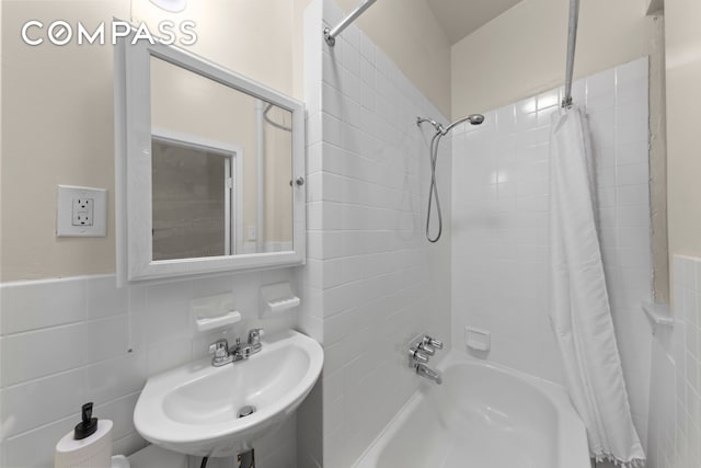 bathroom with tile walls, shower / tub combo, and a sink