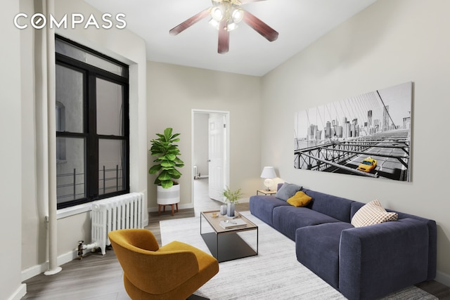 living area with baseboards, radiator, wood finished floors, and a ceiling fan