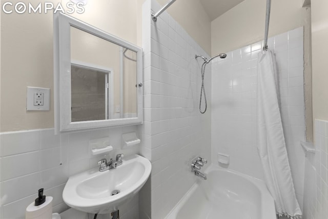 bathroom featuring shower / bathtub combination with curtain, sink, and tile walls