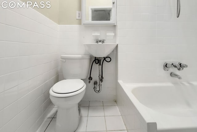 bathroom featuring tile walls, a tub to relax in, tile patterned floors, and toilet