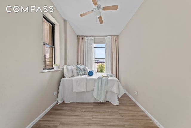 bedroom featuring light wood-style flooring, a ceiling fan, and baseboards