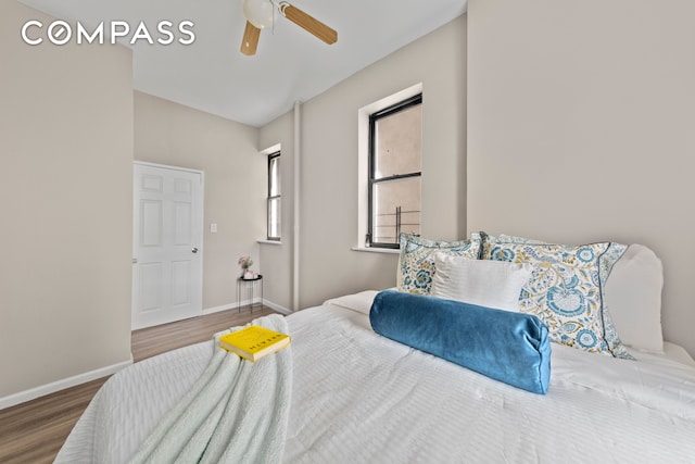 bedroom with baseboards, wood finished floors, and a ceiling fan