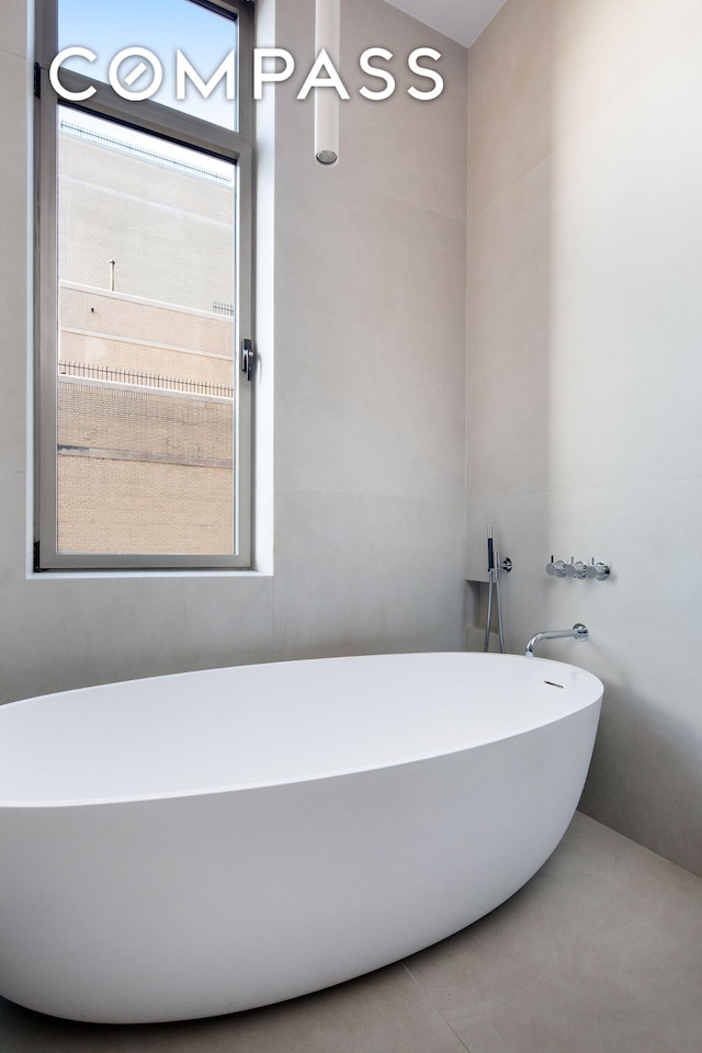 full bathroom with a freestanding tub and tile patterned flooring
