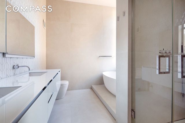 bathroom with tile walls, a shower stall, double vanity, toilet, and a freestanding bath