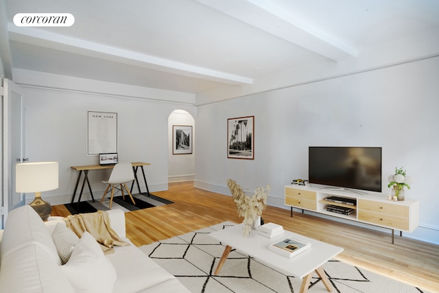 living area with arched walkways, visible vents, beamed ceiling, and wood finished floors