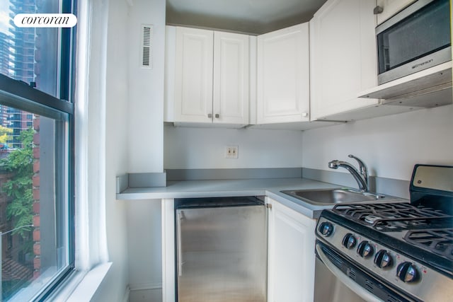 kitchen with a sink, visible vents, white cabinets, light countertops, and appliances with stainless steel finishes