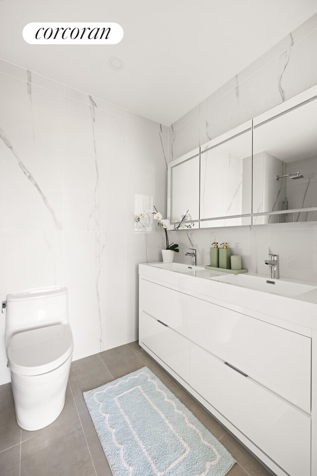 bathroom with double vanity, toilet, tile patterned floors, walk in shower, and a sink