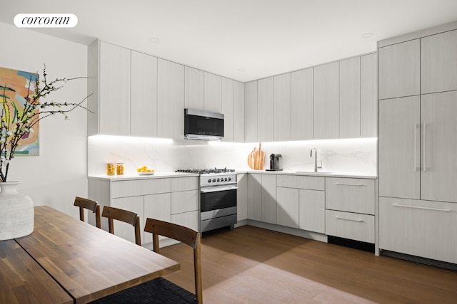 kitchen with stainless steel appliances, sink, light wood-type flooring, and decorative backsplash