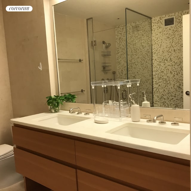 bathroom featuring toilet, vanity, and a shower with door