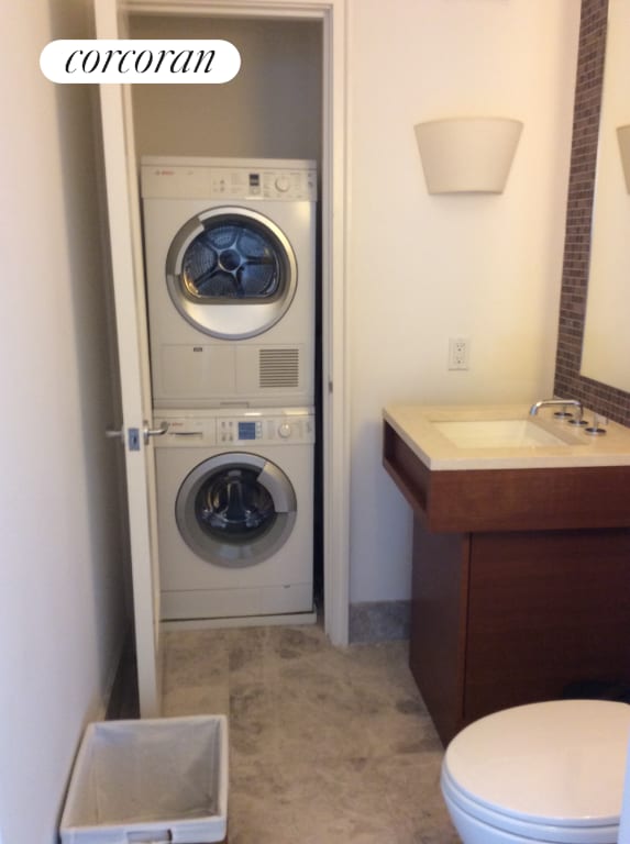 washroom featuring stacked washer and clothes dryer and sink