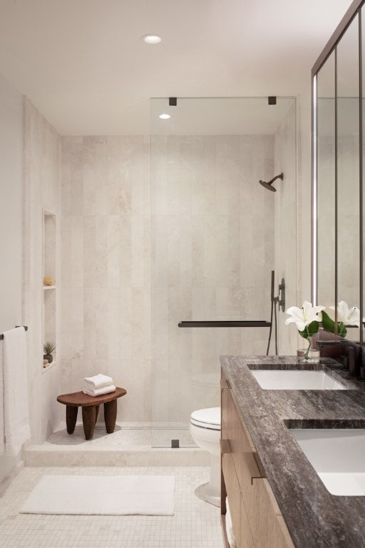 bathroom with walk in shower, vanity, tile patterned flooring, tile walls, and toilet