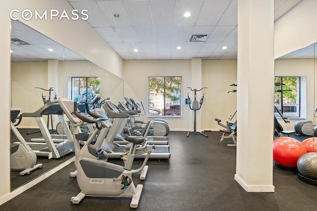 exercise room with a drop ceiling and healthy amount of natural light