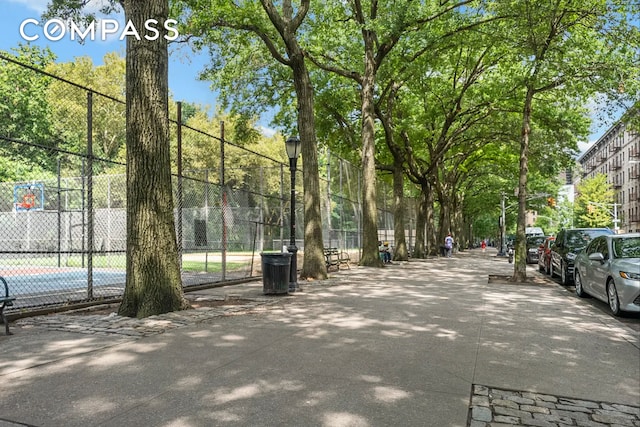 view of community with a tennis court and fence