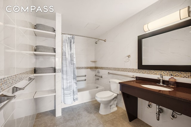full bathroom with a sink, tile walls, shower / bath combo with shower curtain, toilet, and tile patterned floors