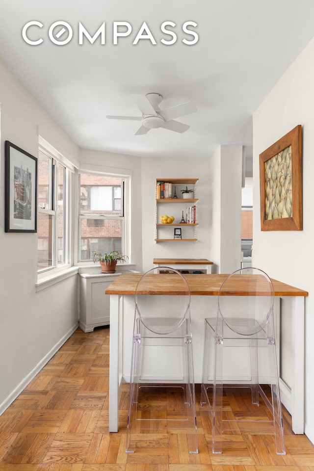 kitchen featuring baseboards, a peninsula, a kitchen bar, open shelves, and wooden counters