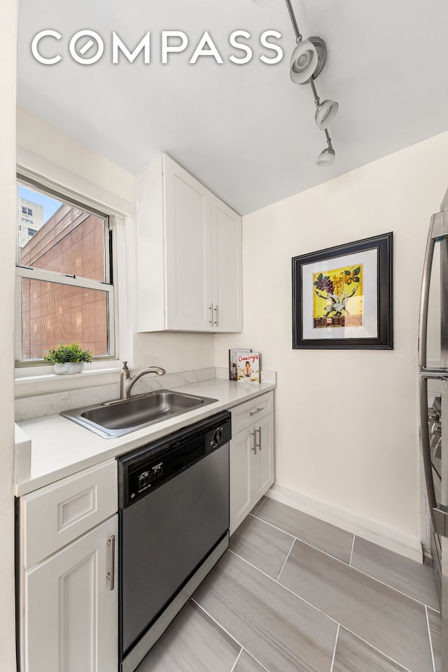 kitchen with stainless steel appliances, a sink, light countertops, and white cabinets