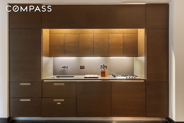 kitchen with dark brown cabinets, sink, and stainless steel gas cooktop