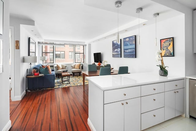 kitchen featuring hanging light fixtures, kitchen peninsula, white cabinetry, and light hardwood / wood-style floors