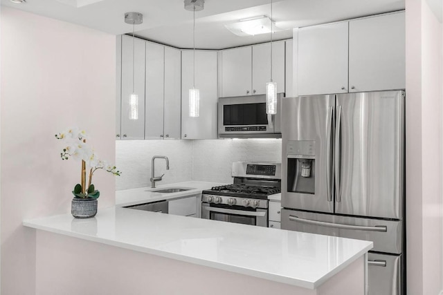 kitchen featuring white cabinets, stainless steel appliances, sink, hanging light fixtures, and kitchen peninsula