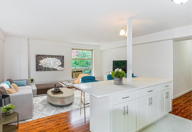 kitchen featuring white cabinets, light stone countertops, and a center island