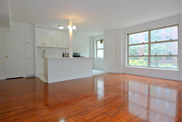 unfurnished living room featuring hardwood / wood-style floors and sink