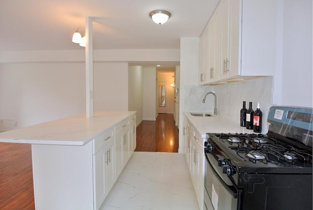 kitchen featuring tasteful backsplash, light stone countertops, black range with gas cooktop, white cabinets, and sink