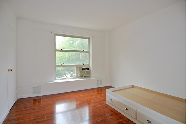 empty room featuring cooling unit, a wealth of natural light, and hardwood / wood-style floors