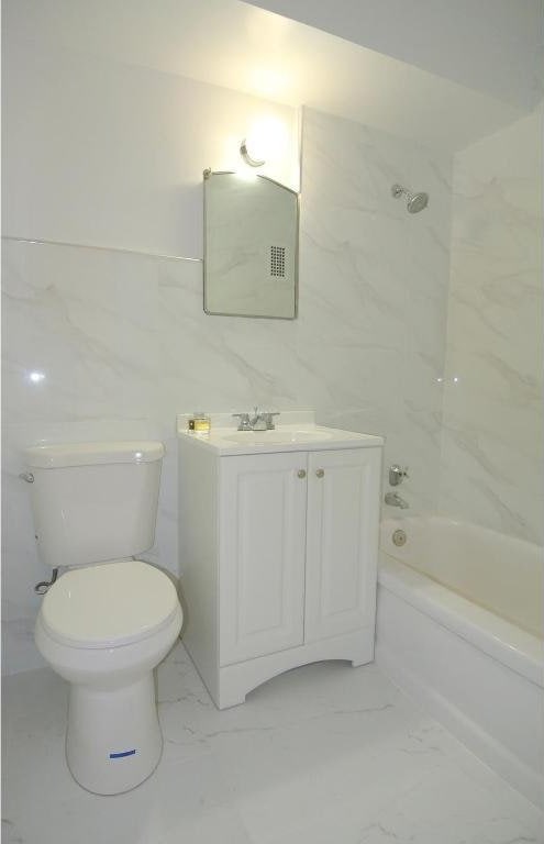 full bathroom with toilet, vanity, and tiled shower / bath combo