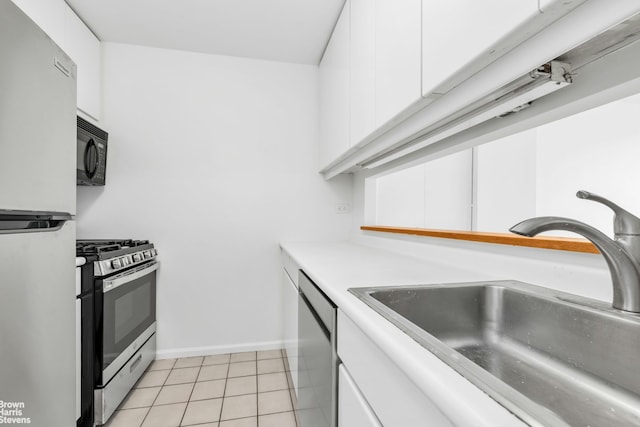 kitchen featuring light tile patterned floors, white cabinets, appliances with stainless steel finishes, light countertops, and a sink