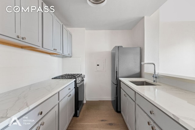 kitchen with gray cabinets, appliances with stainless steel finishes, sink, and light stone counters