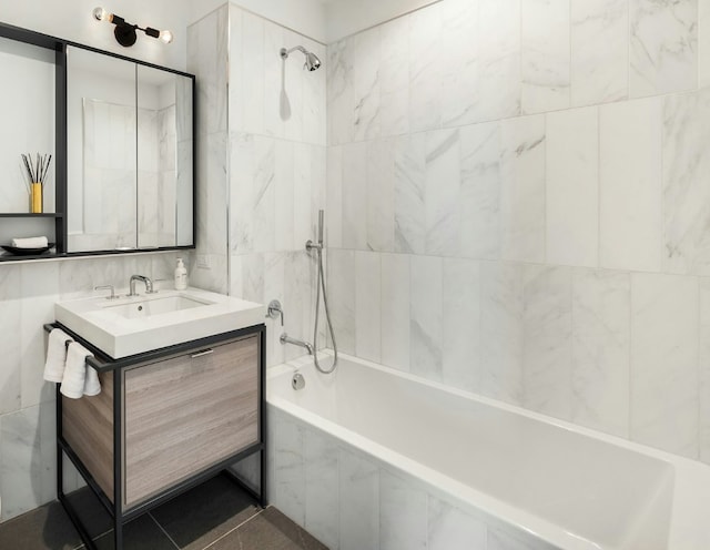 bathroom with vanity, tile patterned flooring, tiled shower / bath combo, and tile walls