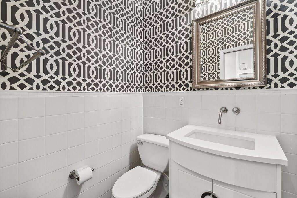 bathroom featuring vanity, tile walls, and toilet