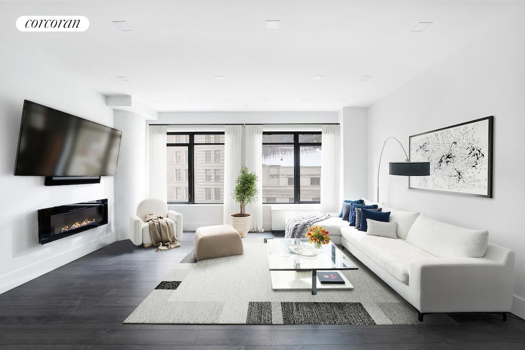 living area with a glass covered fireplace, wood finished floors, and visible vents