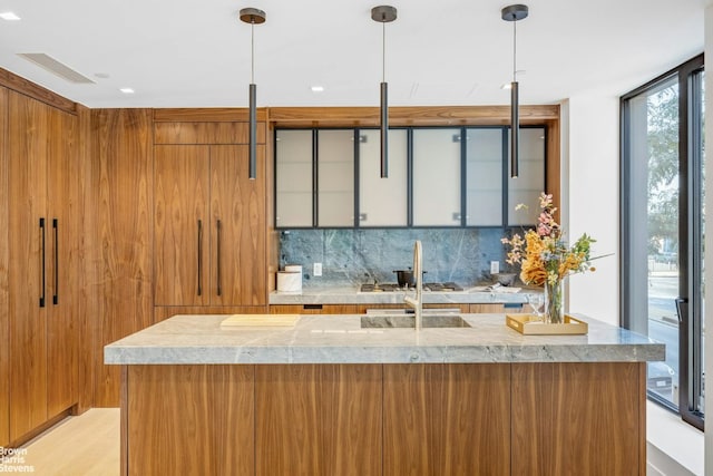 bar featuring sink, a wall of windows, decorative backsplash, decorative light fixtures, and light wood-type flooring