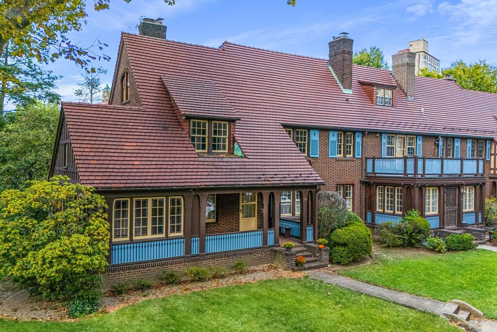 rear view of house featuring a yard, brick siding, a chimney, and a porch