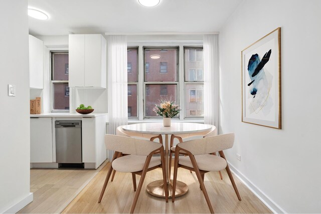 dining area with baseboards, a wealth of natural light, and light wood-style floors