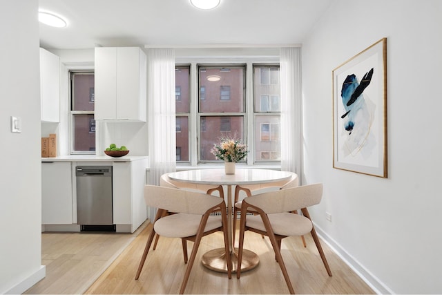 dining area featuring baseboards, a healthy amount of sunlight, and light wood-style flooring