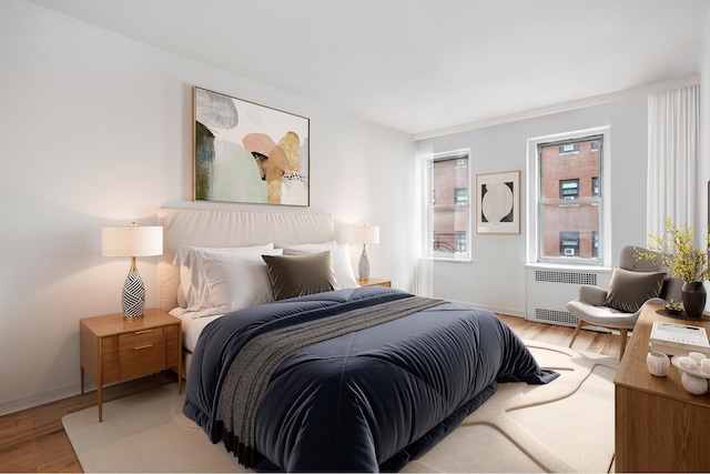 bedroom with baseboards, wood finished floors, and radiator heating unit