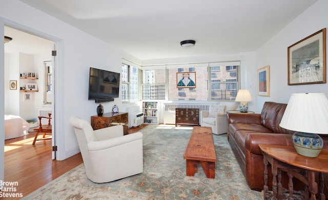 living area with radiator heating unit and wood finished floors