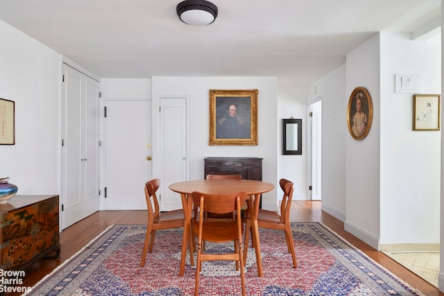 dining area featuring dark wood-style flooring and baseboards