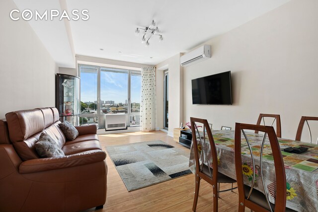 living area with track lighting, light wood-style flooring, and a wall mounted air conditioner