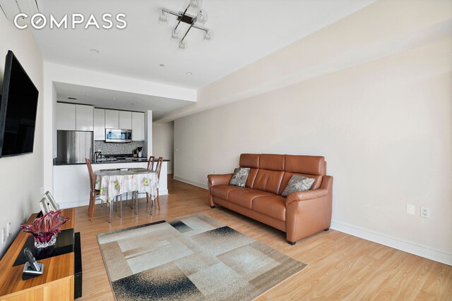 living area featuring light wood-style floors and baseboards