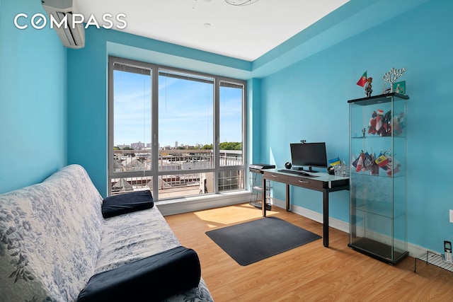 home office with a wall unit AC, wood finished floors, and baseboards