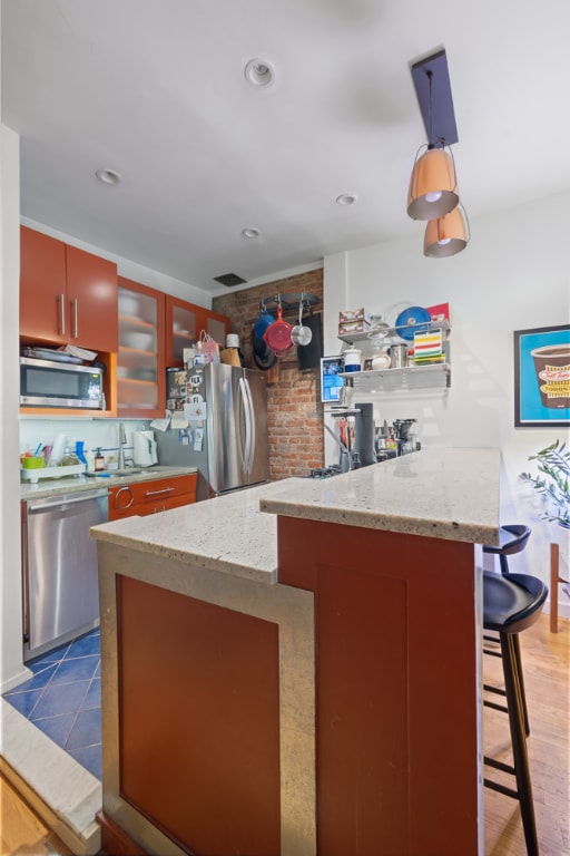 kitchen featuring light stone counters, appliances with stainless steel finishes, a kitchen breakfast bar, and backsplash