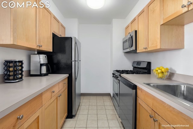 kitchen featuring light tile patterned floors, stainless steel appliances, light brown cabinetry, and sink