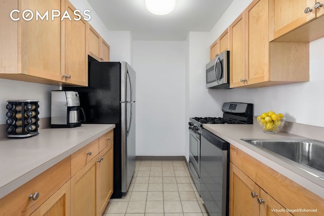 kitchen with appliances with stainless steel finishes, sink, light tile patterned floors, and light brown cabinets