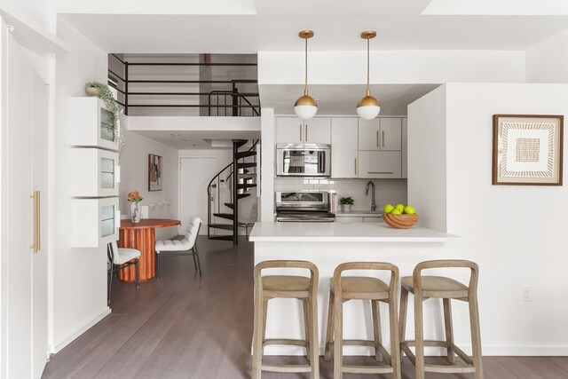 kitchen featuring a kitchen bar, stainless steel appliances, wood finished floors, and light countertops