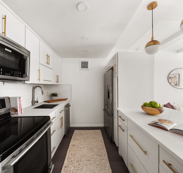 kitchen featuring appliances with stainless steel finishes, dark hardwood / wood-style floors, tasteful backsplash, white cabinetry, and sink